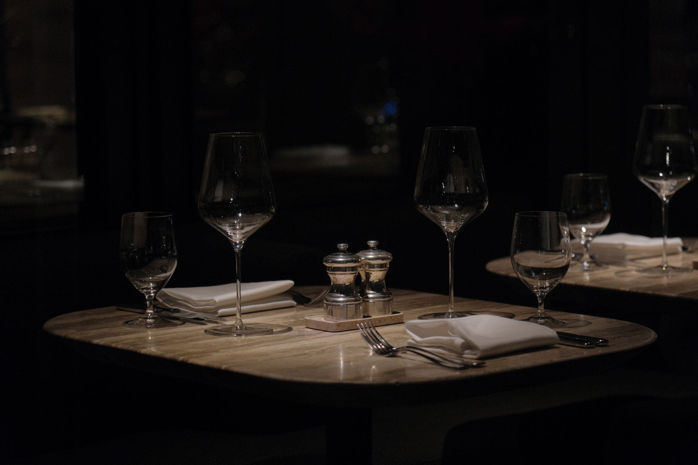 Wine glasses and cutlery on a dark table set for dinner