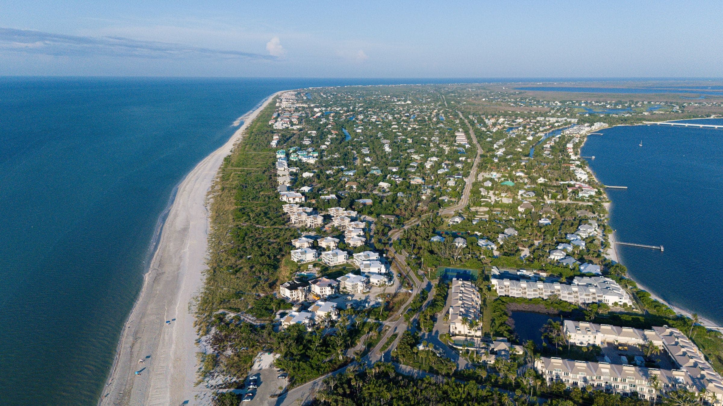 A low-rise beach town along a white sand shoreline, seen from the air