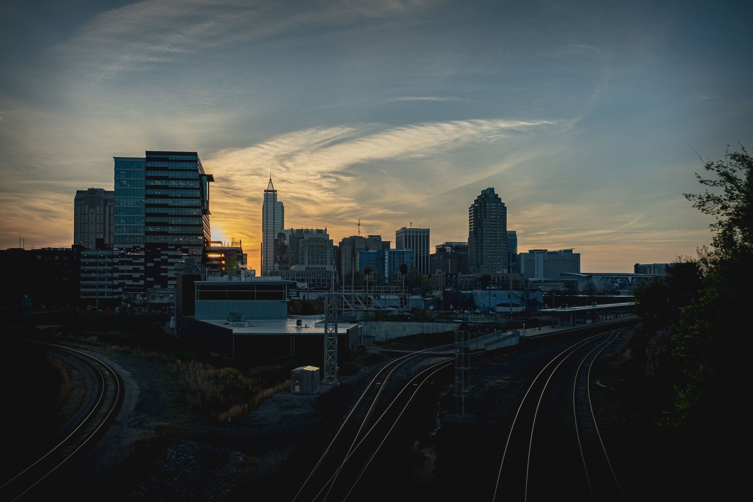 The Charlotte skyline at dusk above the rail corridor