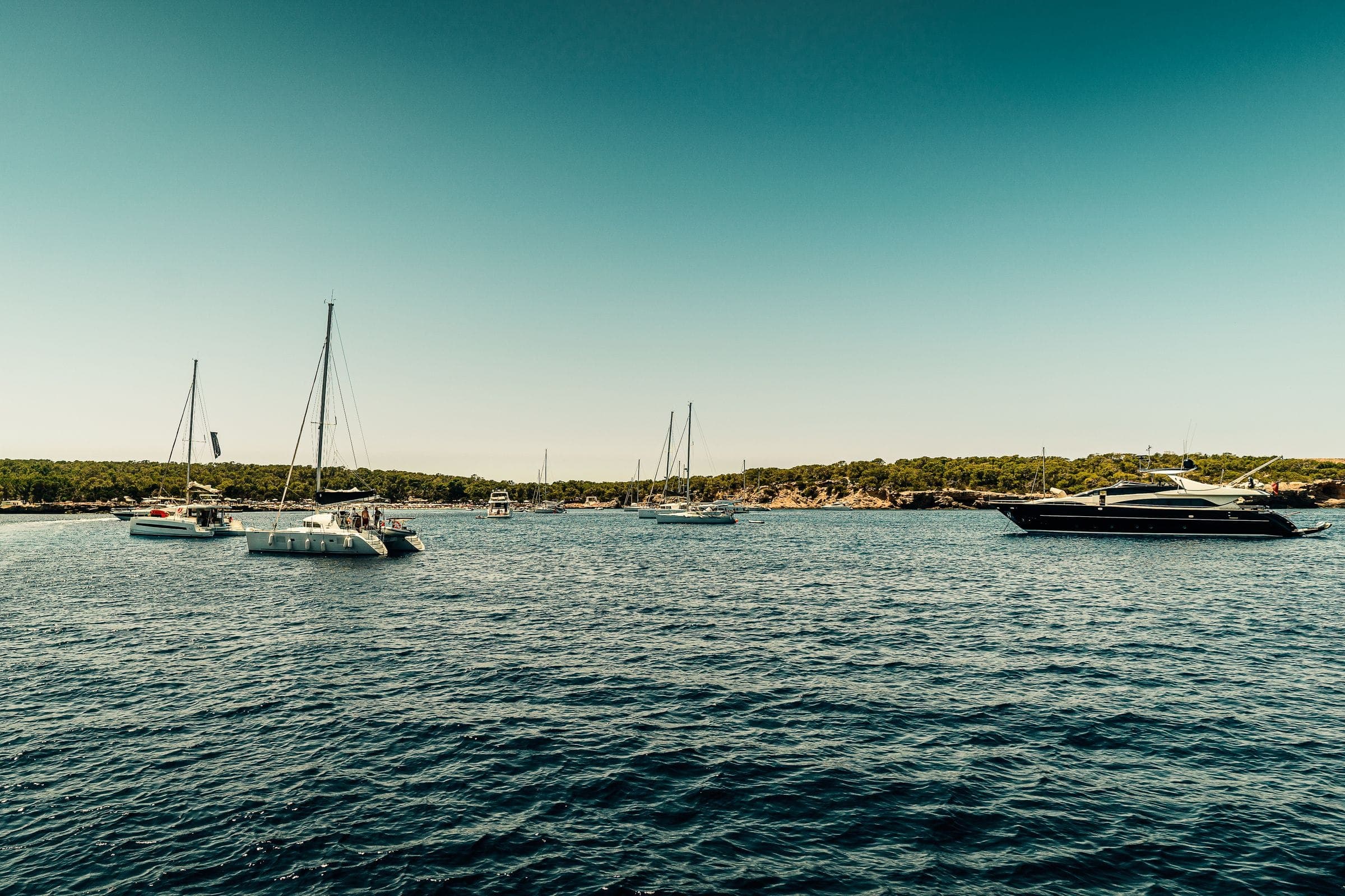Boats anchored off a sandbar in clear green water