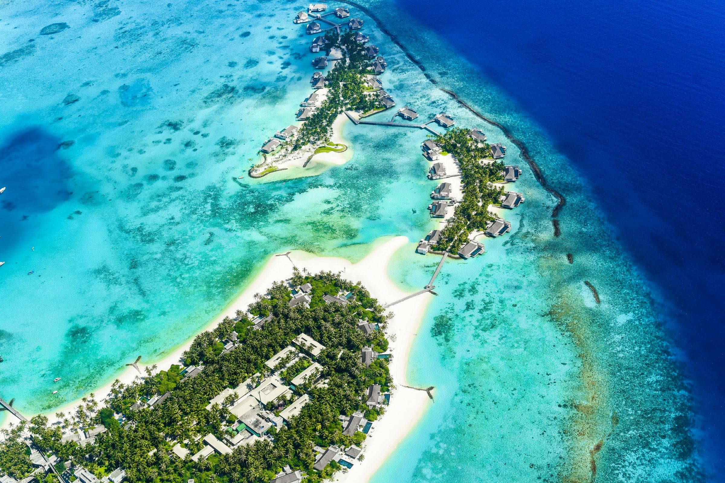 A green island ringed by reef and turquoise shallows, seen from the air