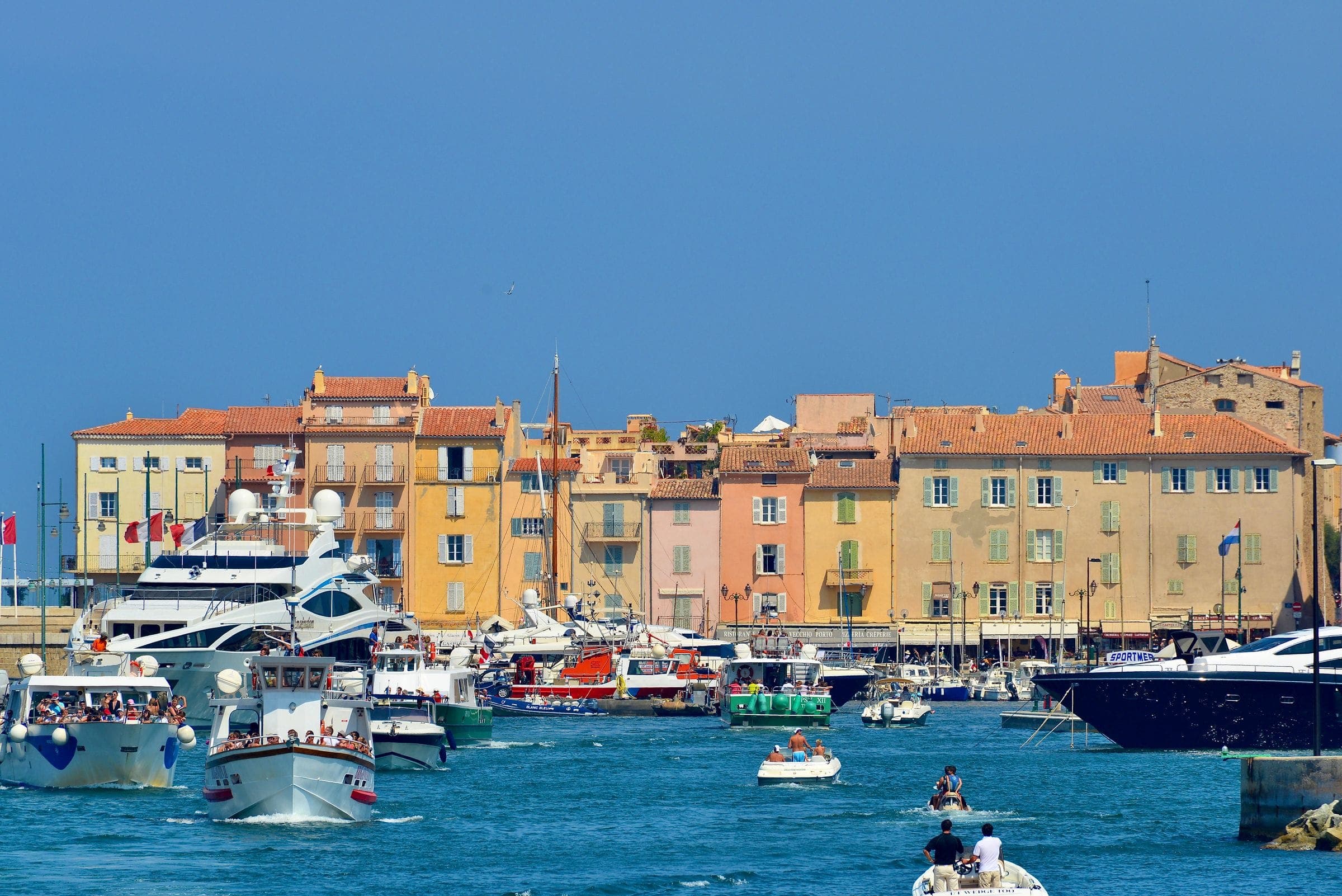 Yachts moored along a harbour front of pastel buildings