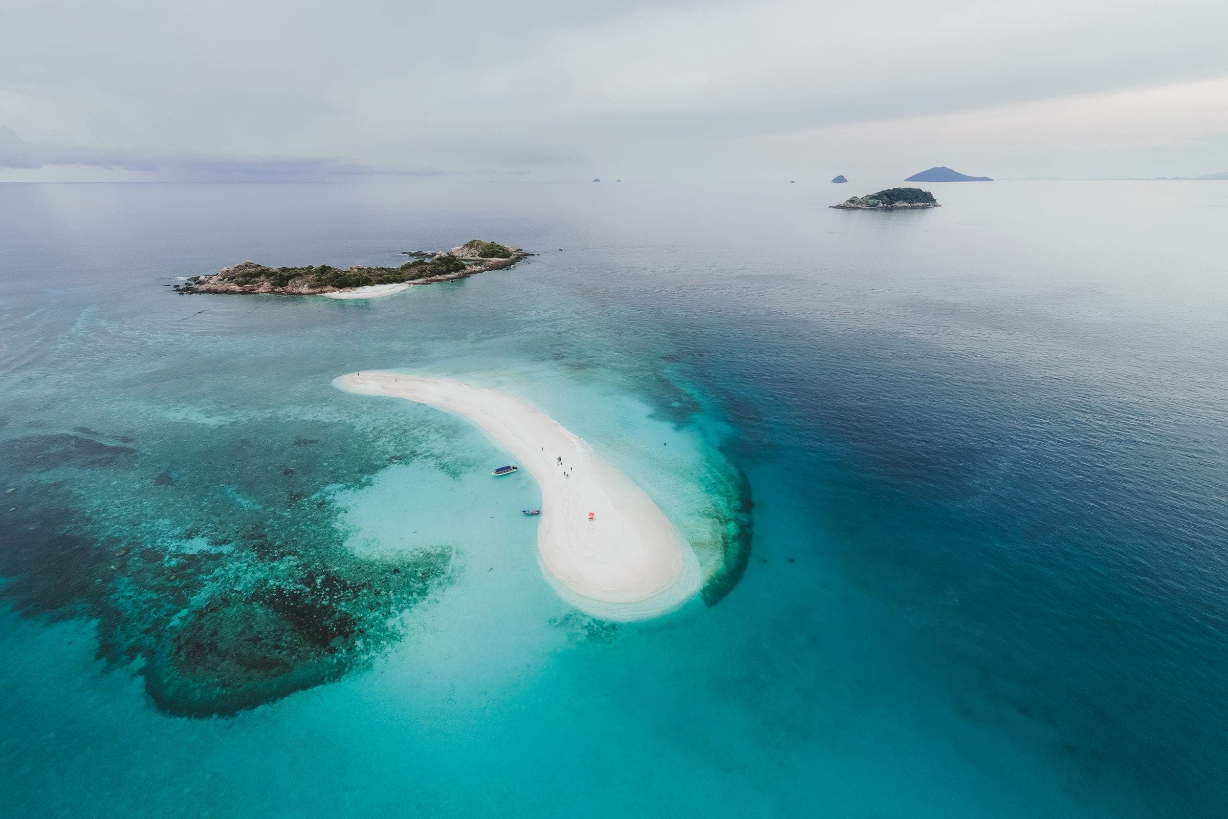 A sandbar curving through turquoise shallows, photographed from height