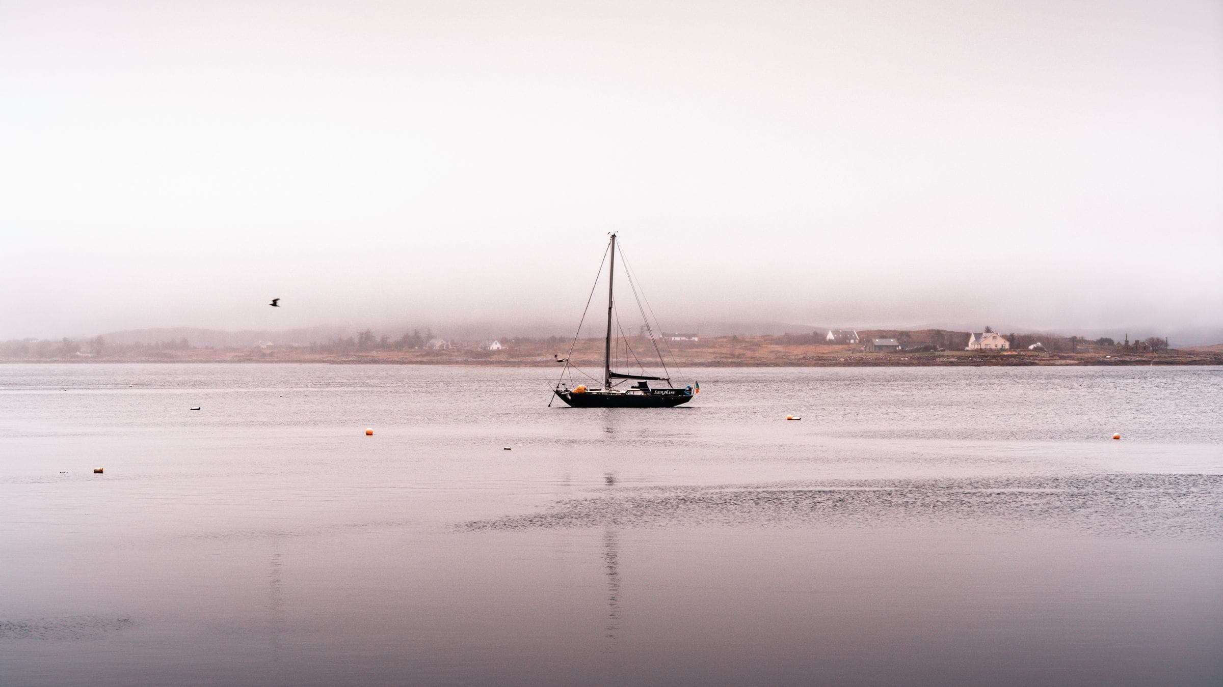A small boat at rest on flat water in soft coastal light