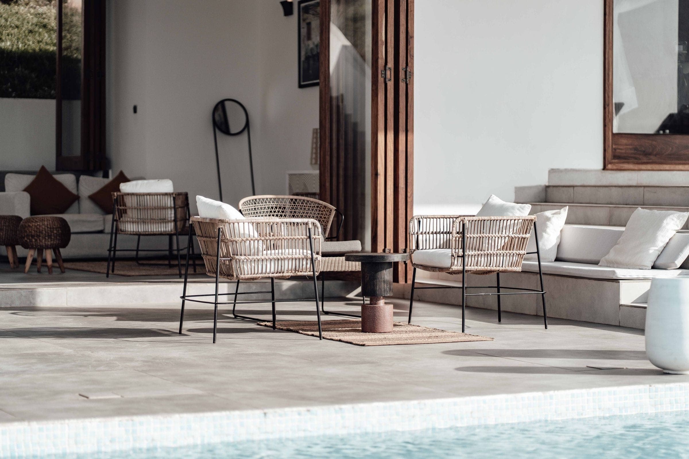 A shaded villa terrace with rattan seating open to the garden