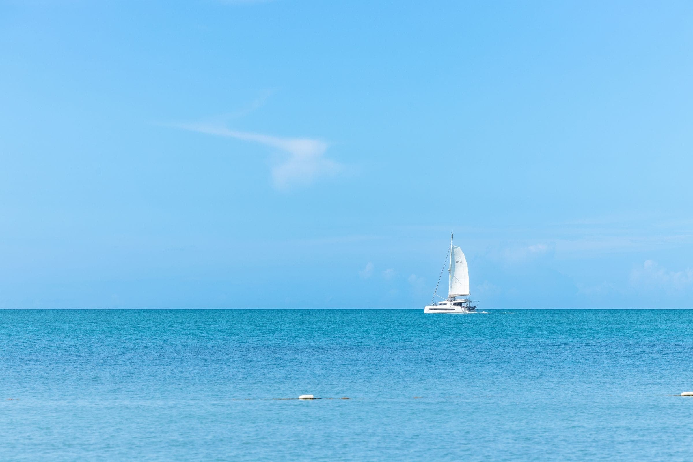 A single sailboat on a wide expanse of turquoise water