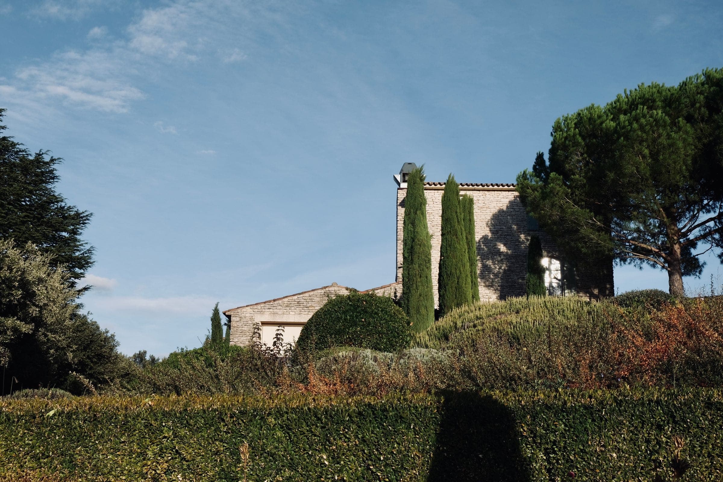 A stone villa behind clipped hedging and cypress