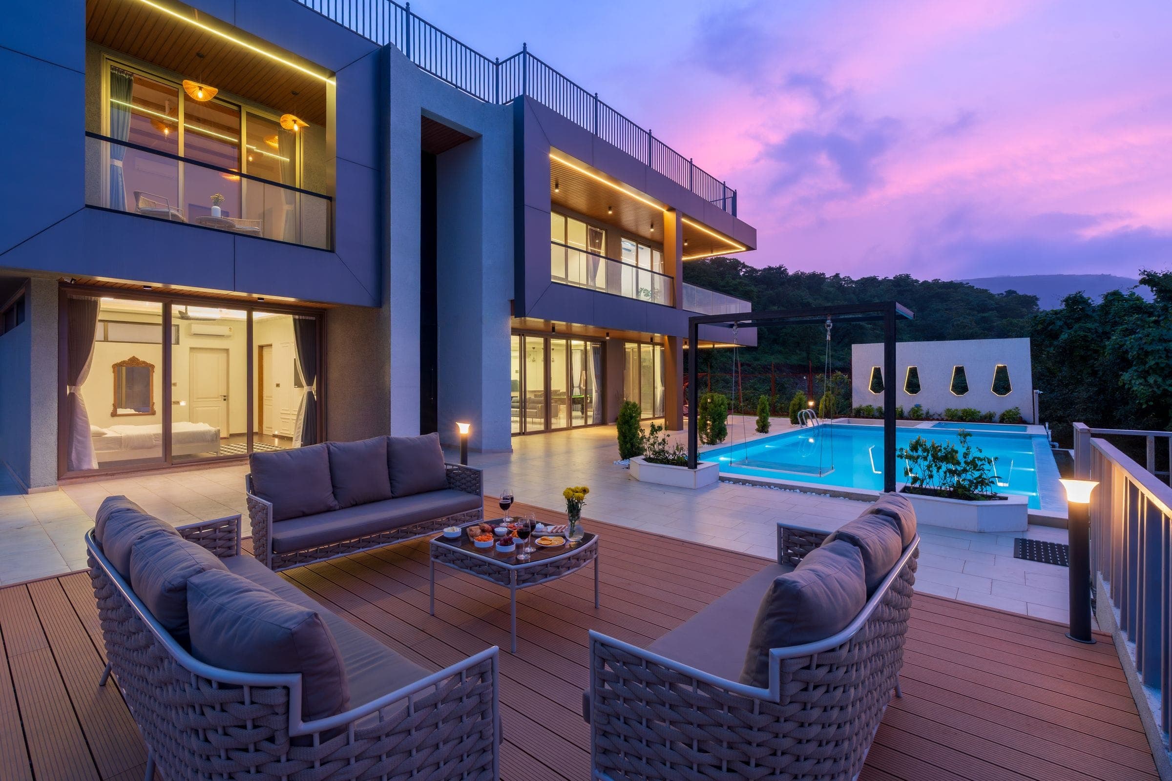 A villa terrace with deep seating, the pool beyond, at dusk